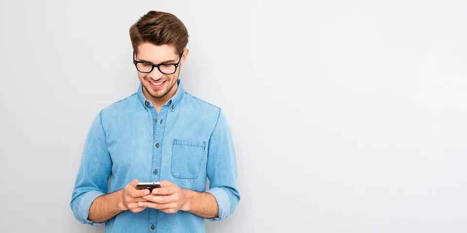 Усміхнений чоловік переглядає смартфон із стабільним мобільним інтернетом від Київстар